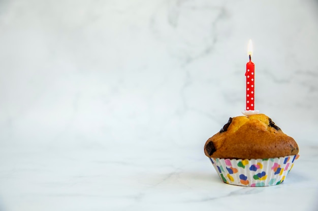 Birthday cupcake with and one red birthday cake candle on a white background with copyspace to side