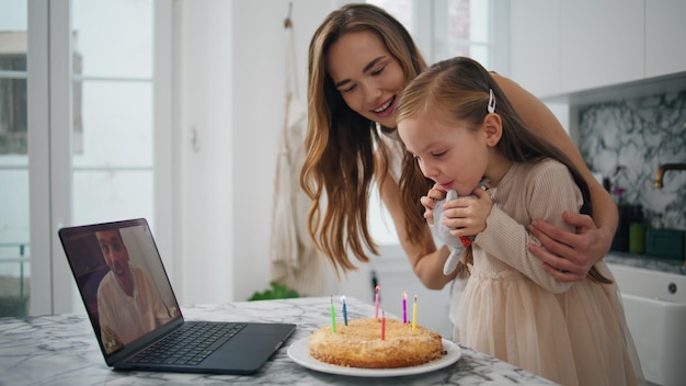 Birthday girl blowing candles kitchen closeup Family celebrating virtual chat