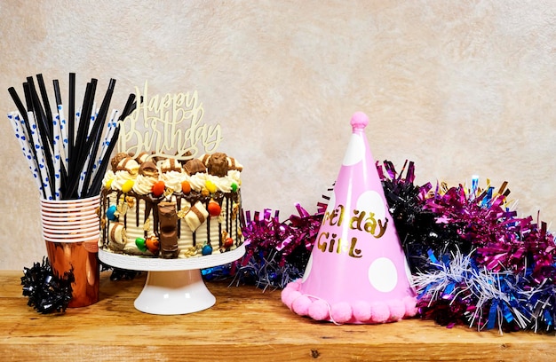 birthday girl party concept layer Cake with happy birthday test and colorful tinsel and disposable