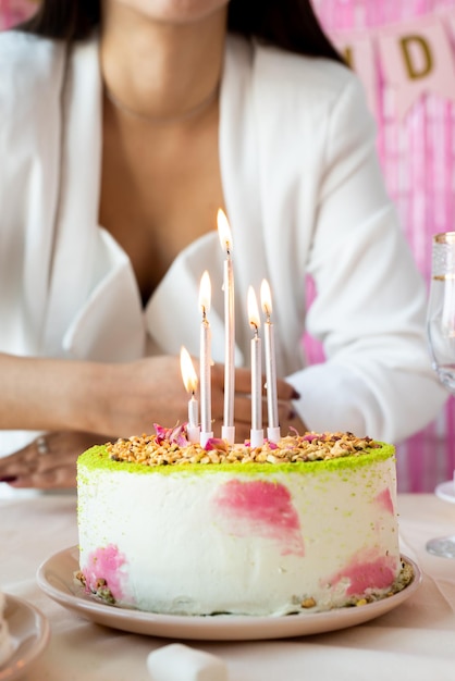 Birthday party Birthday tables Attractive woman in white party clothes preparing birthday table with cakes cakepops macarons and other sweets making wish