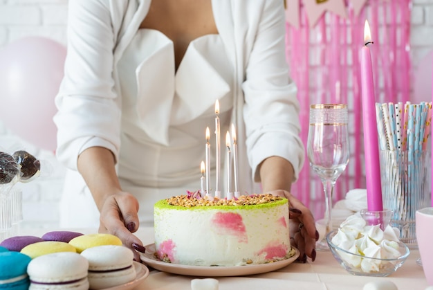 Birthday party Birthday tables Attractive woman in white party clothes preparing birthday table with cakes cakepops macarons and other sweets