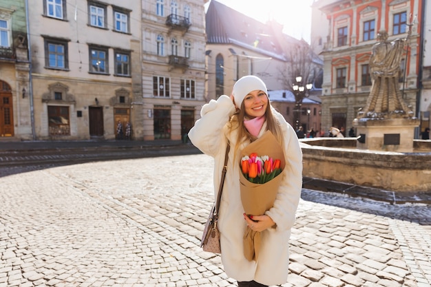 Birthday present for a beautiful girl in a white fur coat Old town square cold sunny day