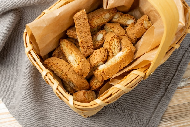 Biscotti di prato on rustic tablecloth burlap background. Traditional italian cantuccini nuts cookies. Homemade cantucci shortbread with almond in a wicker basket