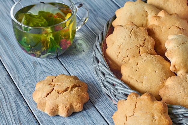 Photo biscuits in the wicker basket from newspaper tubules and a transparent cup of green tea