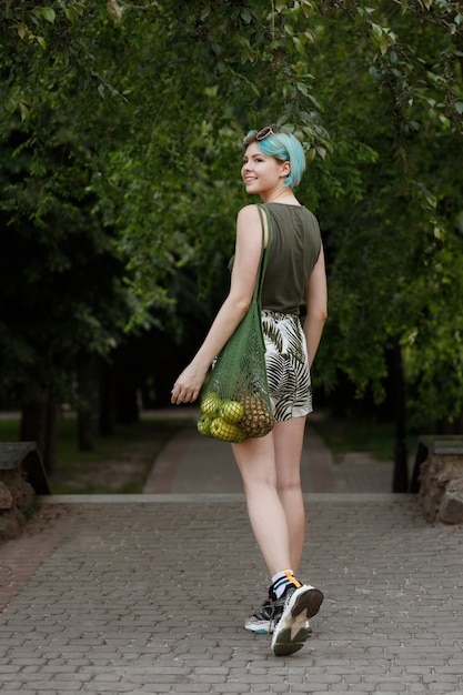 Bisexual girl walks through the park with a bag of fruit. healthy lifestyle