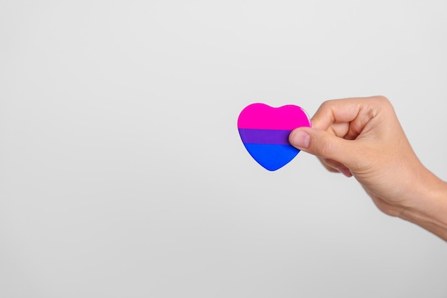 Bisexuality Celebrate Day and LGBT pride month LGBTQ or LGBTQIA concept Hand holding purple pink and blue heart shape for Lesbian Gay Bisexual Transgender Queer and Pansexual community