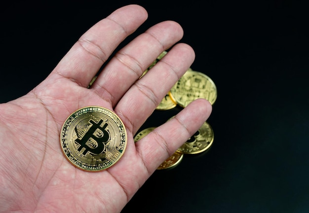 Bitcoin coin placed on the hand on a black background