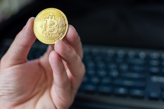 Bitcoin in hand on keyboard background