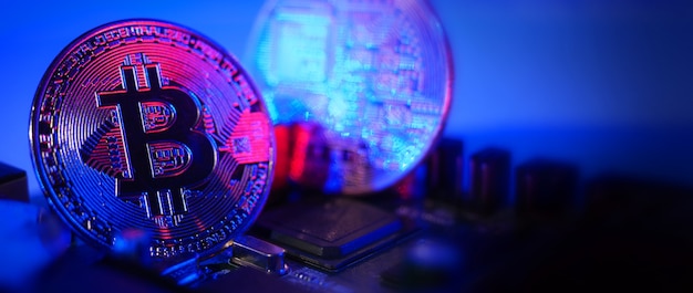 Bitcoin and semiconductor. Represent mining in Cryptocurrency cause global warming. Bitcoins on CPU board. Close-up Bitcoin with blue and pink light. circuit board with coin. Online asset concept.