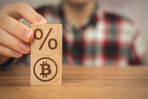 Photo bitcoin and taxes concept background us taxation wooden cubes with bitcoin and percent symbols in hands closeup view business photo