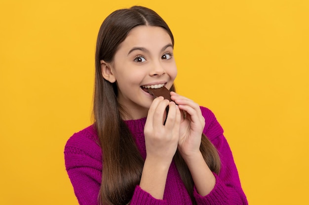 Bite a piece, enjoy a snack. Happy child eat chocolate. Sweet snack. Sweet-tooth yellow background. Taste the depth of deliciousness.