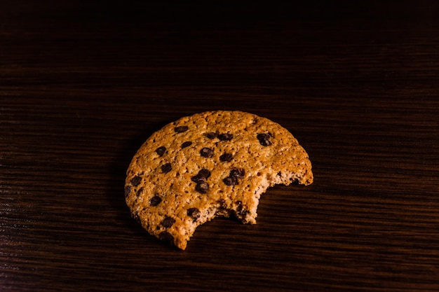 Bitten chocolate chip cookie on a dark wooden table