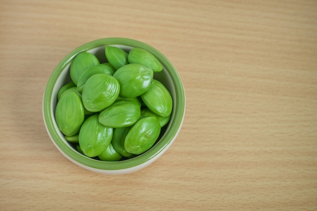 Bitter bean or Twisted cluster bean in cup on wood table. Thai vegetable food.