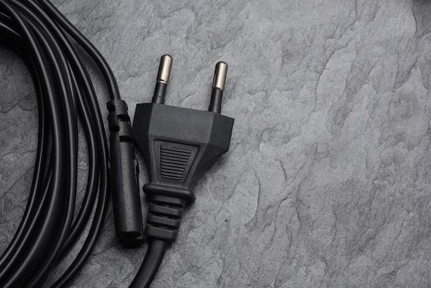 Black AC power plug type C on black slate texture or background