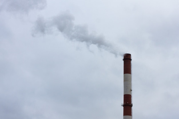 Black acrid smoke from an industrial large chimney over sky. Environmental pollution