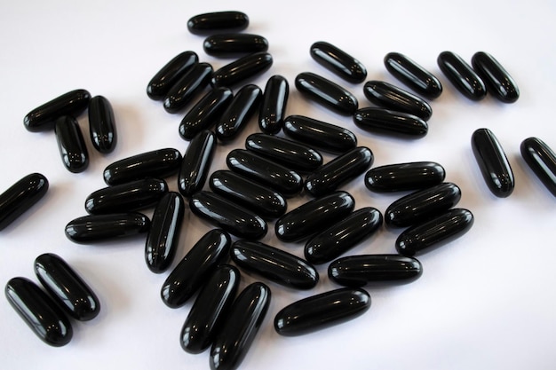 Black Activated Charcoal in capsules on a white background top view Treatment of the digestive system and poisoning