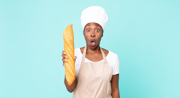 Black african american adult chef woman holding a bread baguette