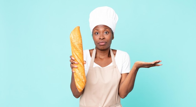 Black african american adult chef woman holding a bread baguette