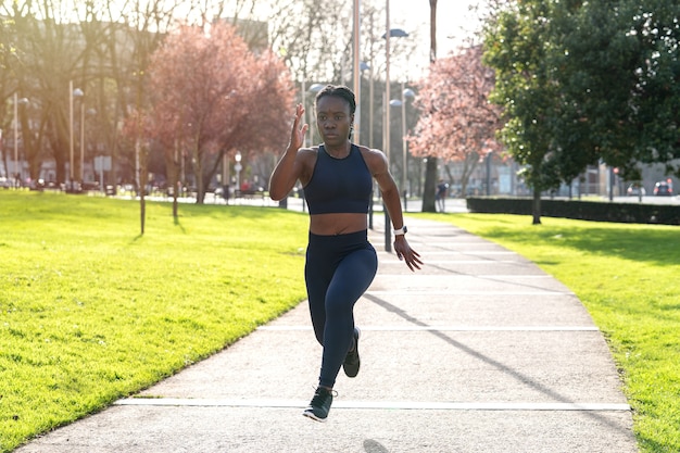 Black afro girl running in a public park at sunset