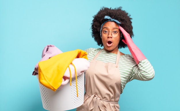 Black afro woman looking happy, astonished and surprised, smiling and realizing amazing and incredible good news. housekeeping concept.. household concept