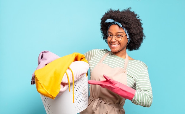 Black afro woman smiling cheerfully, feeling happy and showing a concept in copy space with palm of hand. housekeeping concept.. household concept