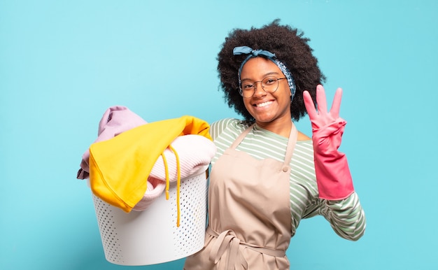 Black afro woman smiling and looking friendly, showing number three or third with hand forward, counting down. housekeeping concept.. household concept