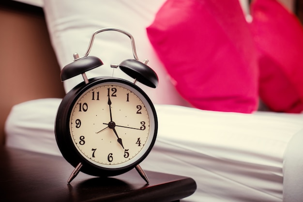 Black alarm clock in the bedroom and with red pillows