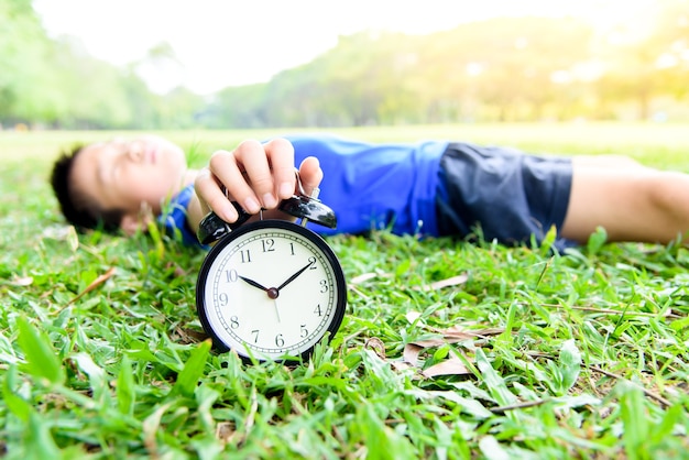 Black alarm clock and sleeping boy in the park