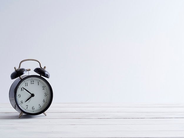 Black alarm clock on white wooden.