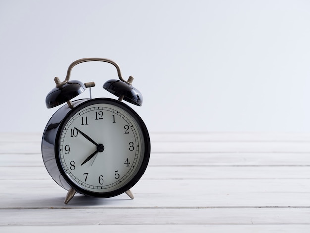 Black alarm clock on white wooden.