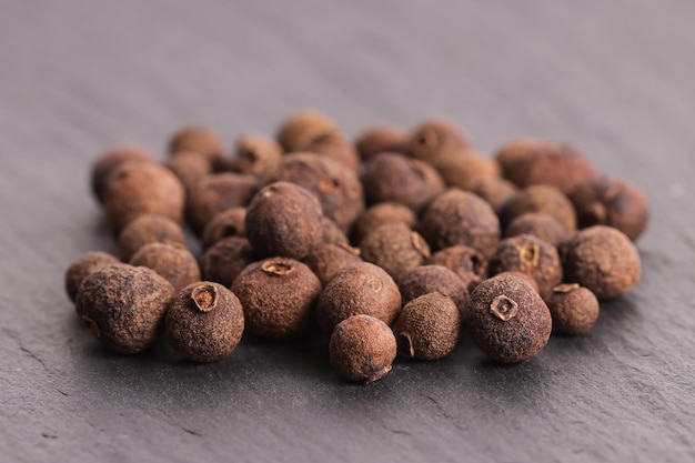 Black allspice in peas on a stone gray plate