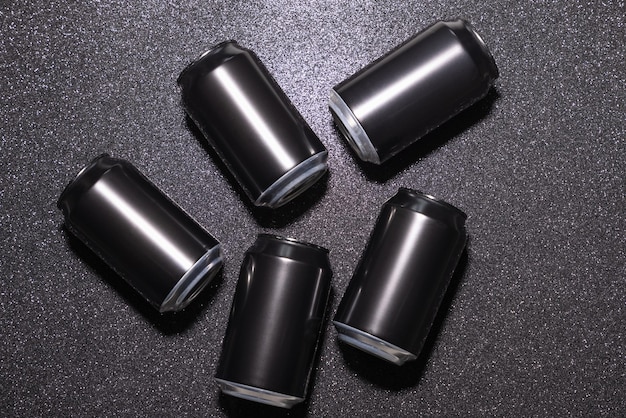 Photo black aluminium soda cans on a black background with sparkles view from above