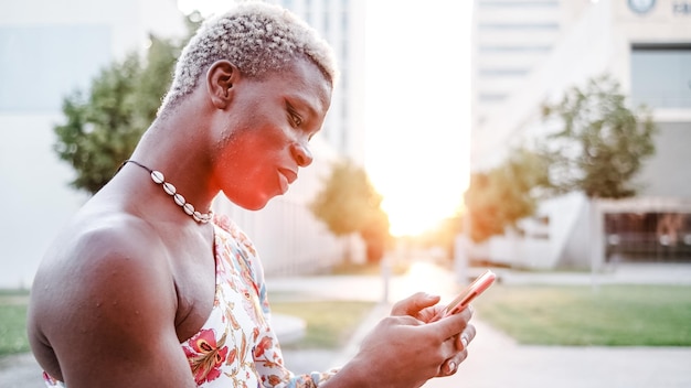 Black androgynous man using smartphone on street