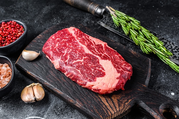 Black angus ribeye, raw ribeye beef steak on a wooden board with knife.