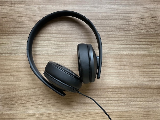 Black aroundear headphones lying on wooden desk