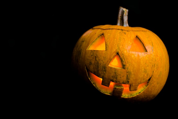 On the black background is a terrible pumpkin with carved teeth Decoration for Halloween