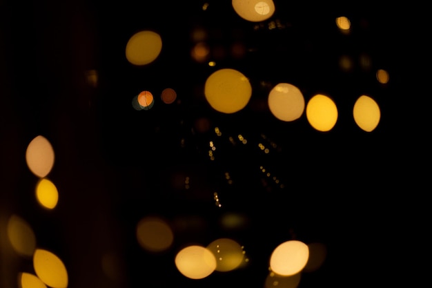 Black background with golden glittering lights bokeh. abstract defocused pattern with grain effect