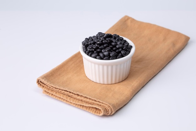 Black bean in white bowl on cloth and white background studio shot