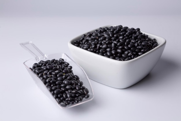 Black bean in white bowl and plastic spoon on white background studio shot