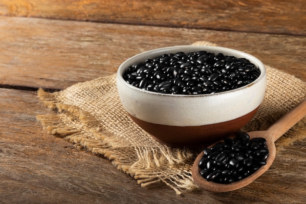 Black beans in wooden spoon and ceramic bowl