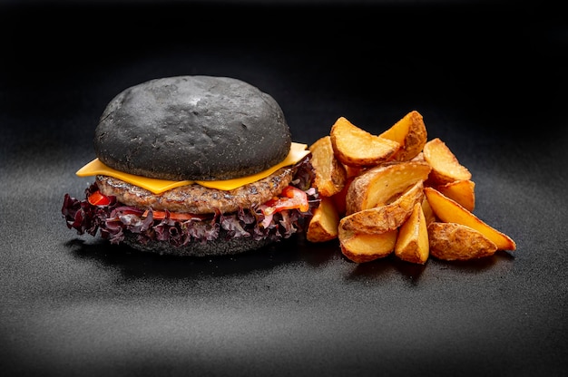 Black beef burger with french fries isolated on black background