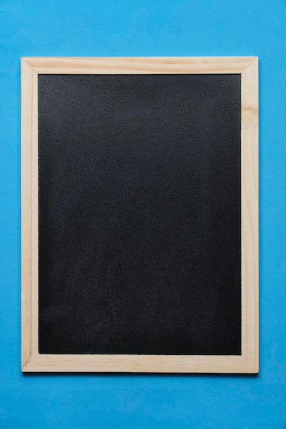 Black blackboard for notes in wooden frame blue background