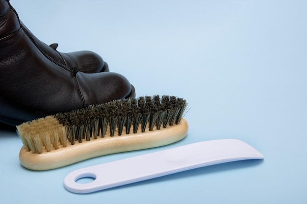 Black boots with a brush and a shoe horn on a blue background