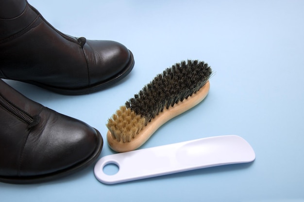 Black boots with a shoehorn and a brush on a blue background