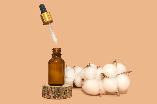 Black bottle of cosmetic lotion with a branch of cotton On a wooden podium