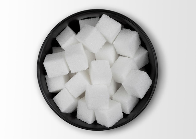 Black bowl of natural white sugar cubes on white