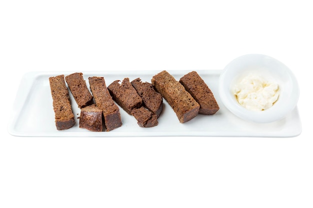 Black bread croutons with sauce in a white snack plate Appetizing popular snack for beer Closeup Top view Isolated on white background