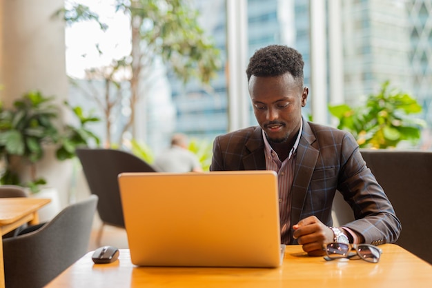 Black businessman using laptop computer at coffee shop