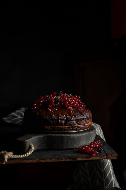 A black cake with red berries on a black stone surface