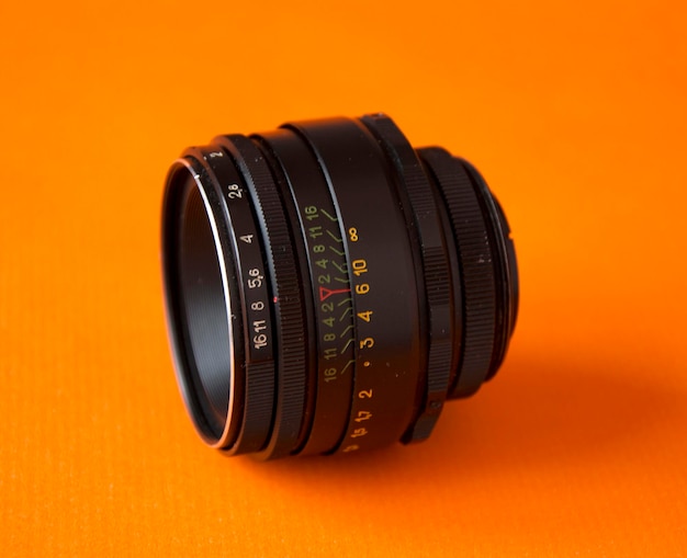 Black camera lens isolated on an orange background